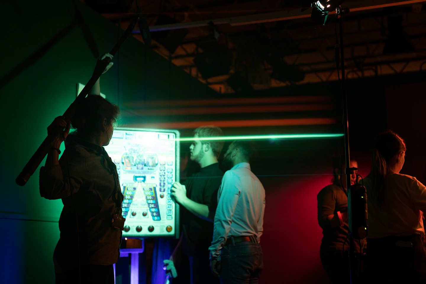 People play an interactive arcade game in a neon-lit room.